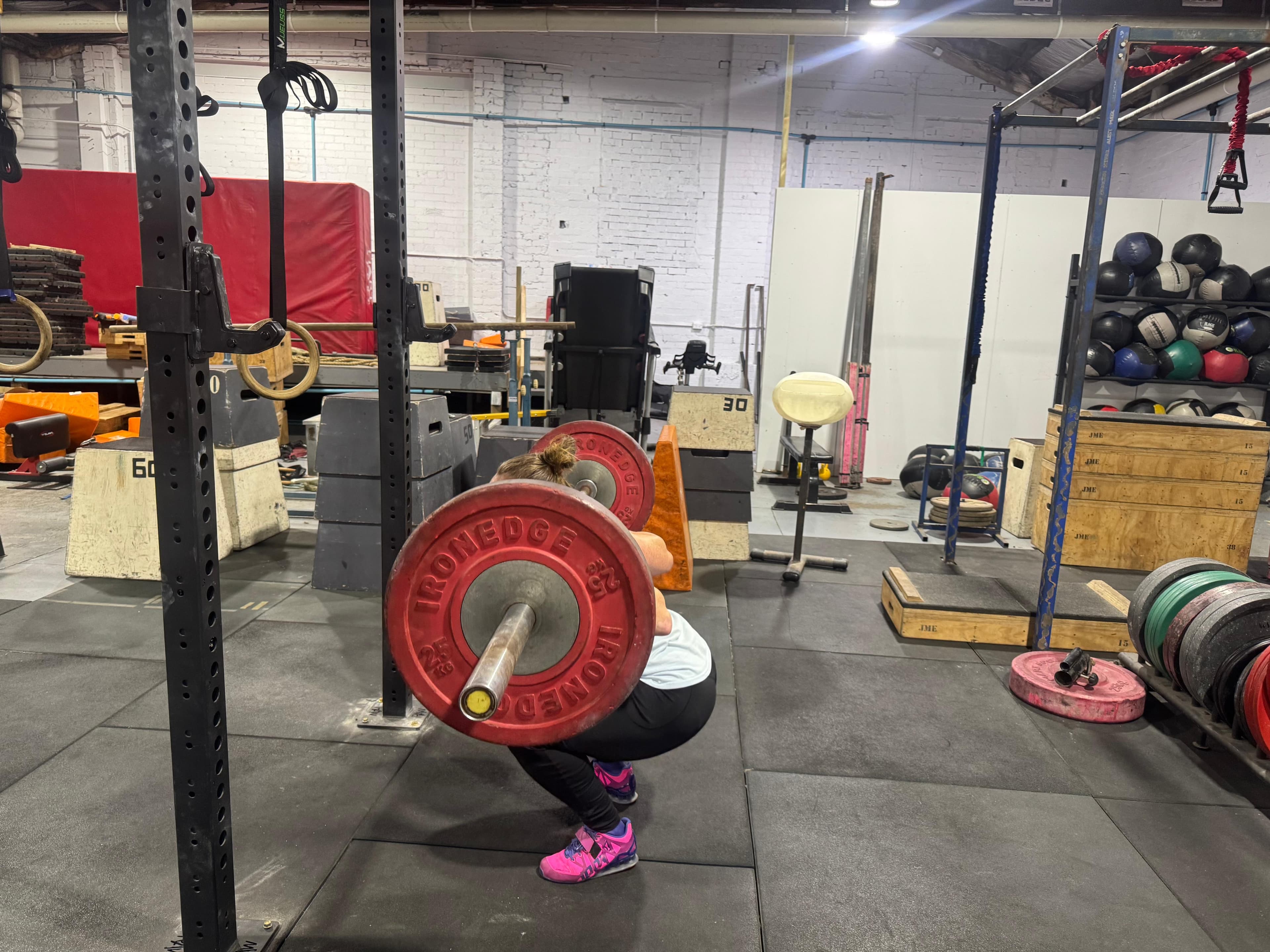 A member in a deep front squat with red bumper plates